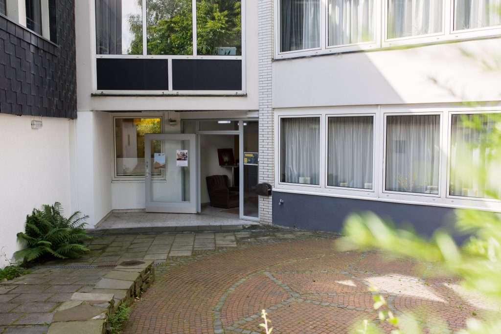 Ein modern gestalteter Hauseingang mit einem Weg und Pflanzen im Vordergrund.